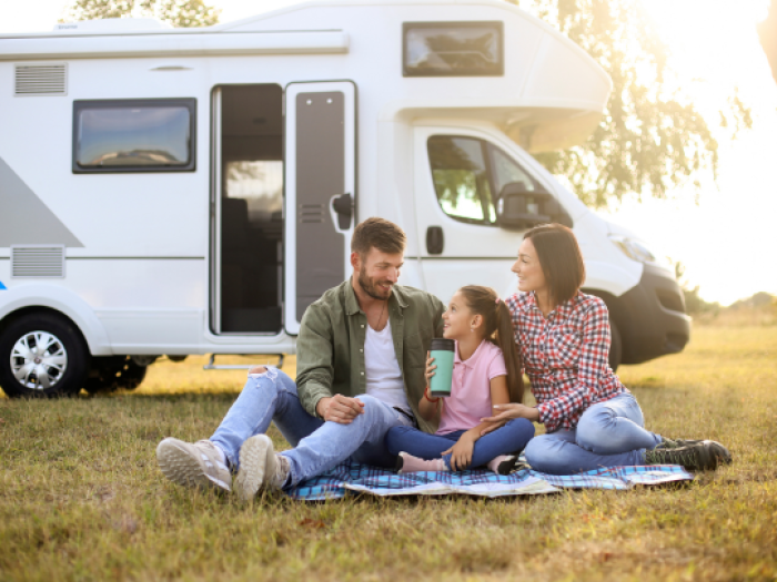 a family sitting on a picnic blanket by their rv secured with an rv loan from essential credit union in plaquemine