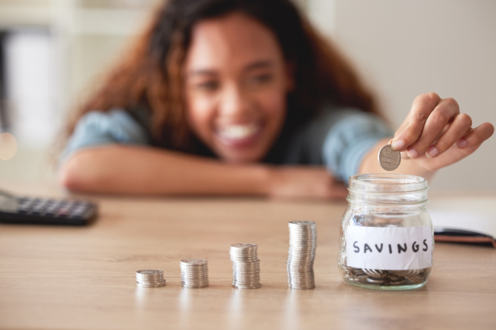 a young woman stacking quarters in her savings jar - youth savings account in gonzales