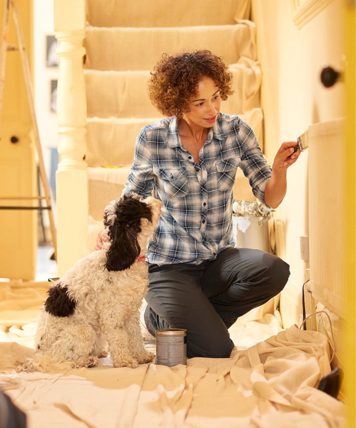 Woman painting her walls while petting her dog